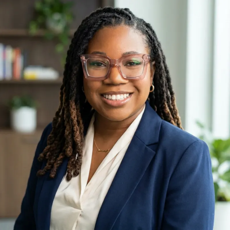 Kierra McClellan smiling in a navy blazer and glasses